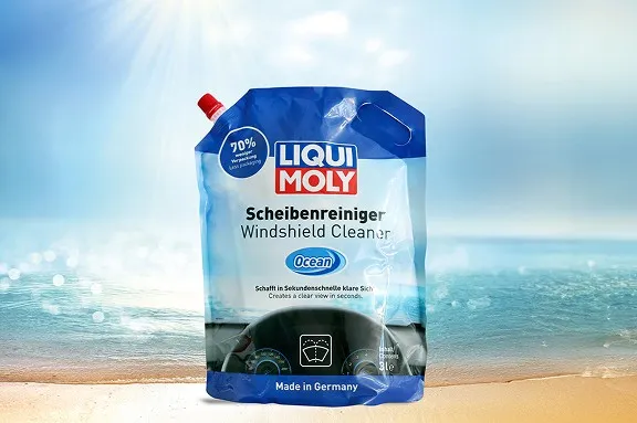 Blauer Liqui Moly Scheibenreiniger-Beutel der Sorte Ocean vor einem sonnigen Strandhintergrund.